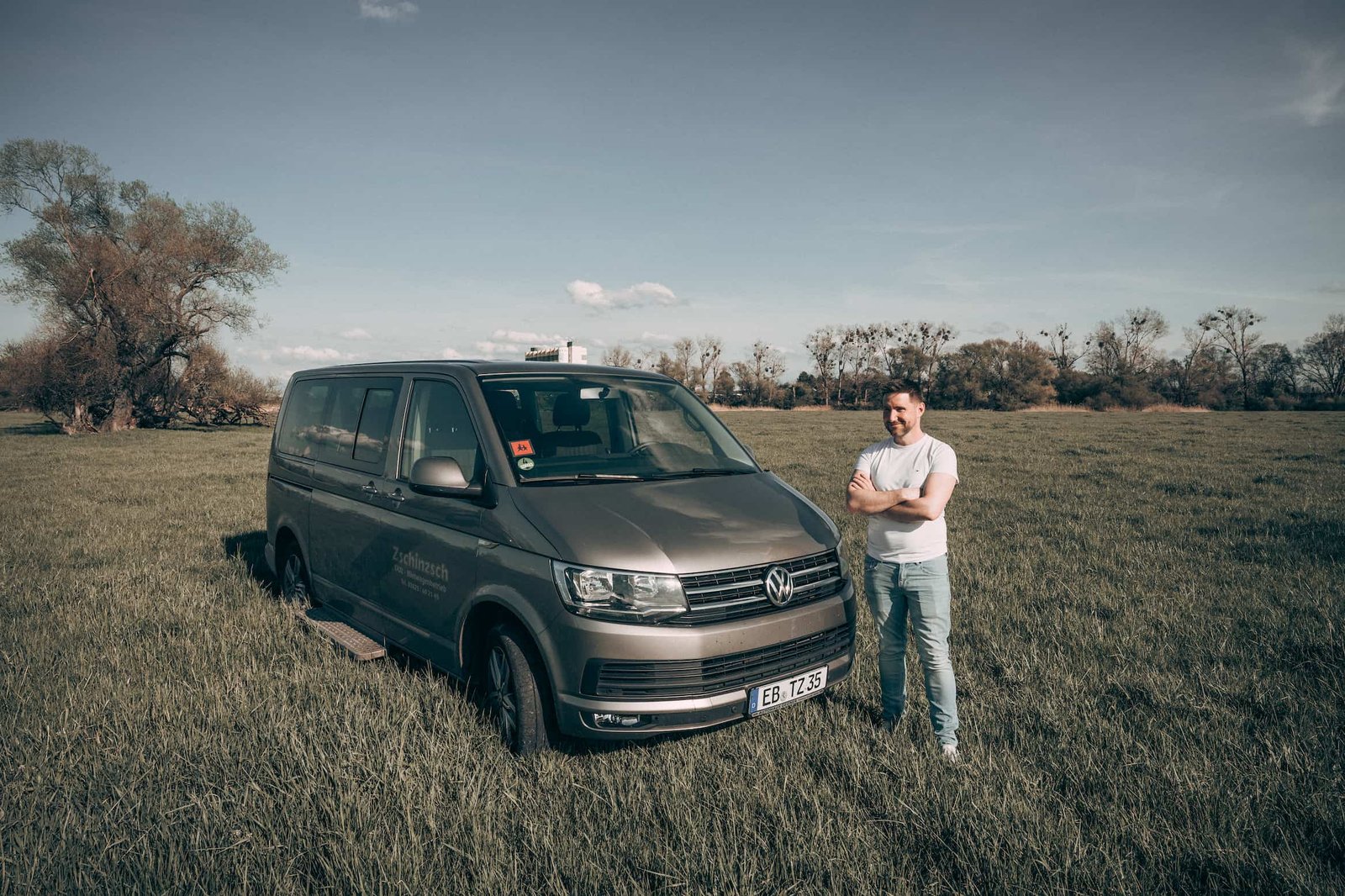 Inhaber Rico Zschinzsch steht neben einem VW Multivan des Fuhrparks